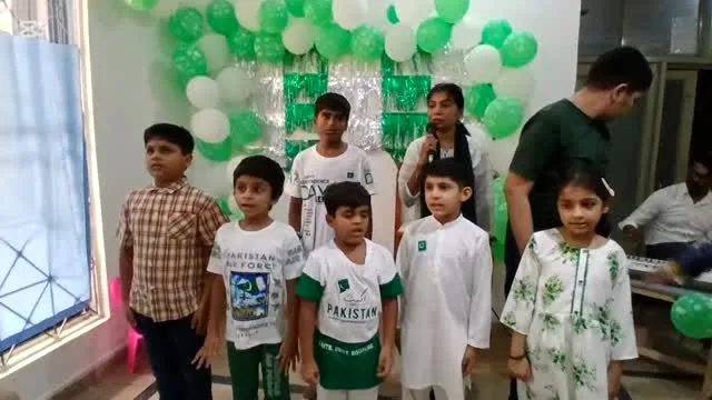 Children at Care Nest singing together on Independence Day, green and white balloons behind them